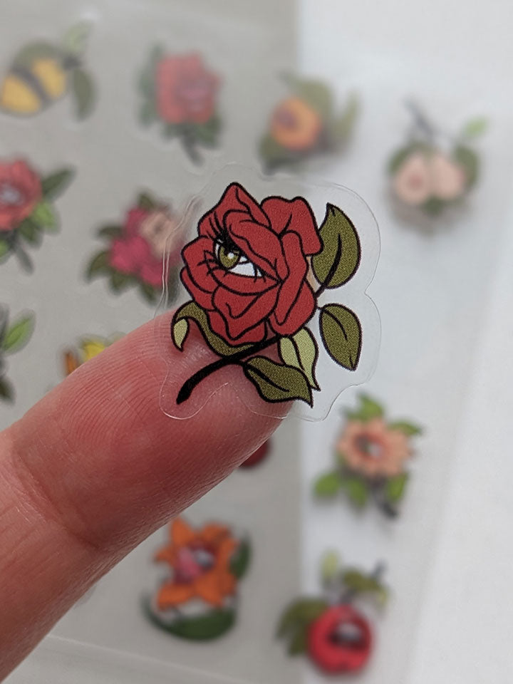 Original art sticker sheet, semi-transparent material. collection of surreal illustrations of different flowers, zoom on a red rose with a green eye by useless treasures. 