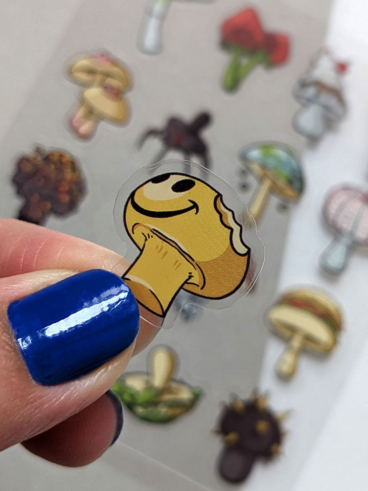 Original art sticker sheet, semi-transparent material. collection of surreal illustrations of different mushrooms, zoom on a smiling yellow mushroom by useless treasures. 