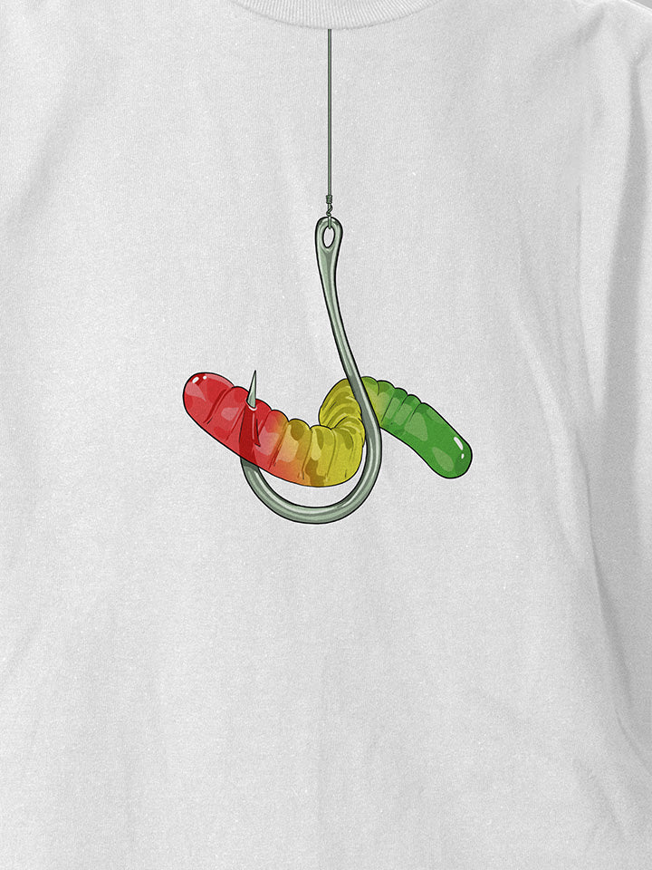 A close-up of a white printed t-shirt by useless treasures. Print of an illustration of colorful gummy warm hung on a silver hook. 