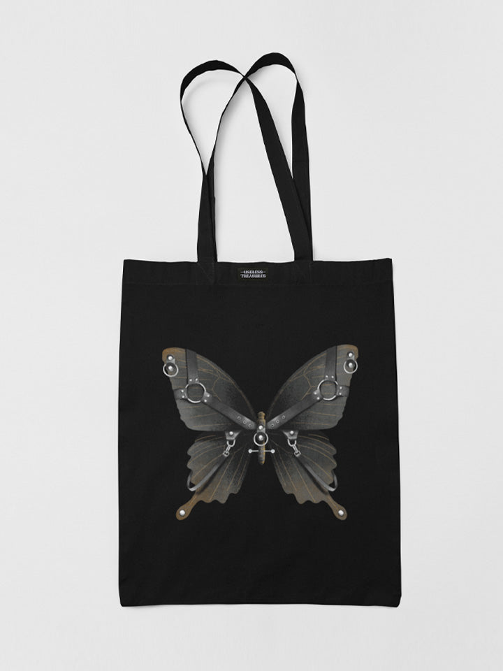 A black tote bag printed with a black butterfly with a harness. A design by contemporary Berlin artist "Useless Treasures".The tote bag is made from organic cotton and is fairly sourced. This wearable art piece is in the spirit of Berlin gallery art, Berlin techno, and Berlin clubs. 