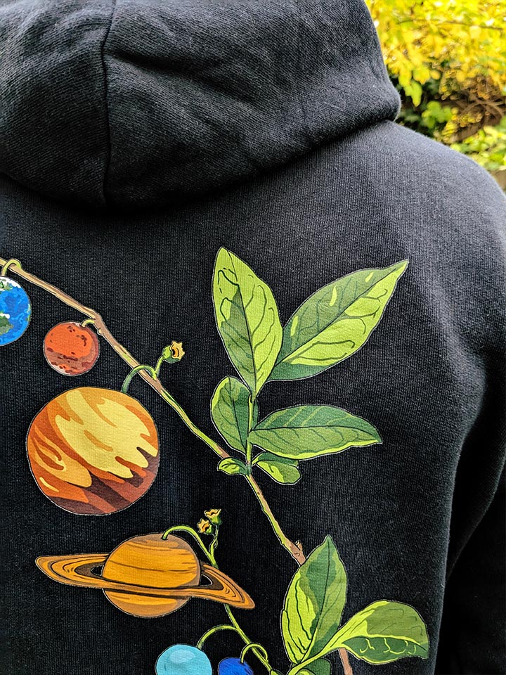 Close-up to a back print detail of a printed hoodie by useless treasures. a branch with planets A work by underground Berlin artist "Useless Treasures".