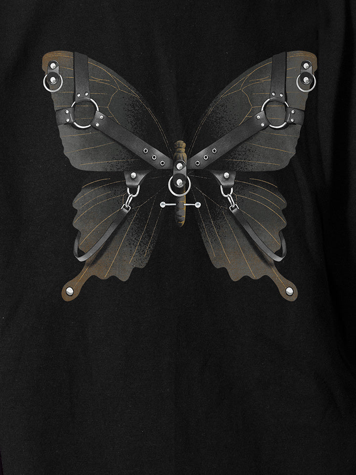 A close-up of a black printed t-shirt by useless treasures. Print of an illustrated black butterfly with leather gear and silver chains​ and piercings. 
