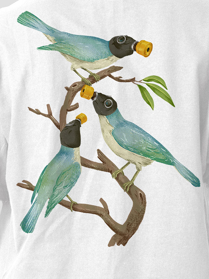 A close-up of a white printed t-shirt by useless treasures. Print of an illustration of three blue birds with gas masks sitting on a branch with a few green leaves. 