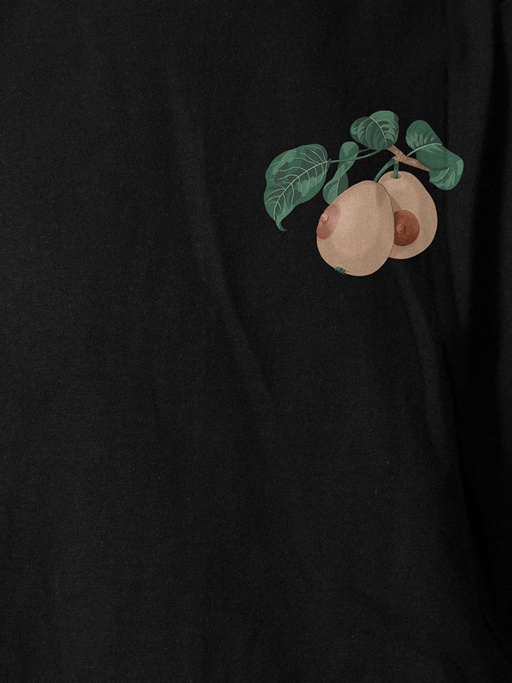 A close-up of a black printed t-shirt by useless treasures. Print of a small illustrated front detail of a pair of boobs hangs on a branch with green leaves. 
