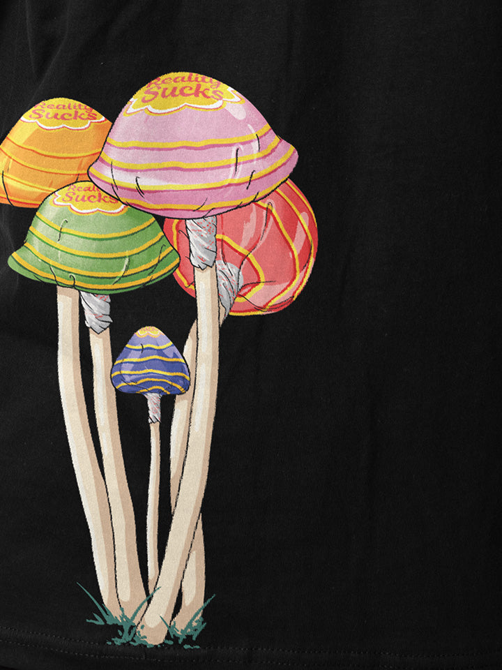A close-up of a black printed t-shirt by useless treasures. Print of an illustrated​bunch of magic psychedelic mushrooms wrapped in a lollypop wrap saying reality sucks. 
