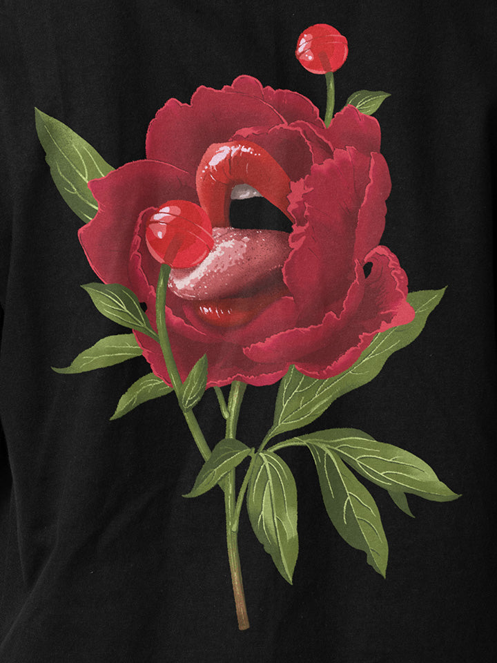 A close-up of a black printed t-shirt by useless treasures. Print of an illustrated red rose with big beautiful lips liking red candy flower.