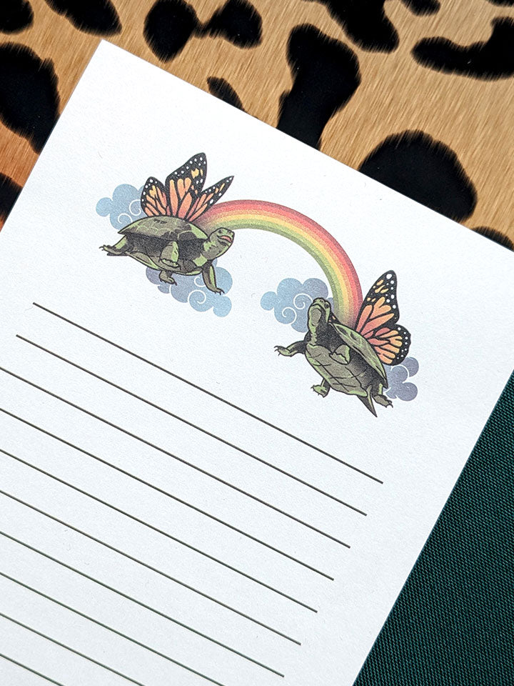 unique notepad with a humorous illustration decoration of two cute turtles with butterfly wings and a rainbow. 