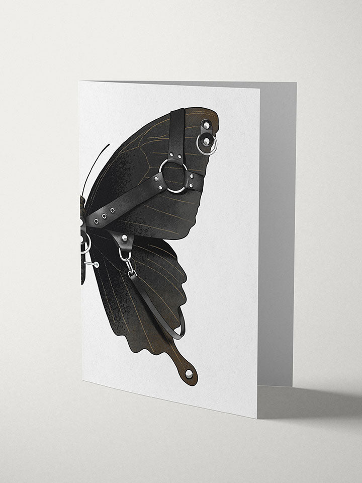 A6 greeting card with an Illustration of a Black butterfly with a leather harness and piercing on top of white background  - Art by useless treasures