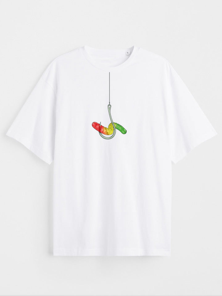 A White oversize printed T-shirt. Short sleeve Shirt with a print called "temptation" of a silver hook holding a colorful gummy warm. Surreal illustration by useless treasures. Organic cotton, loose fit.